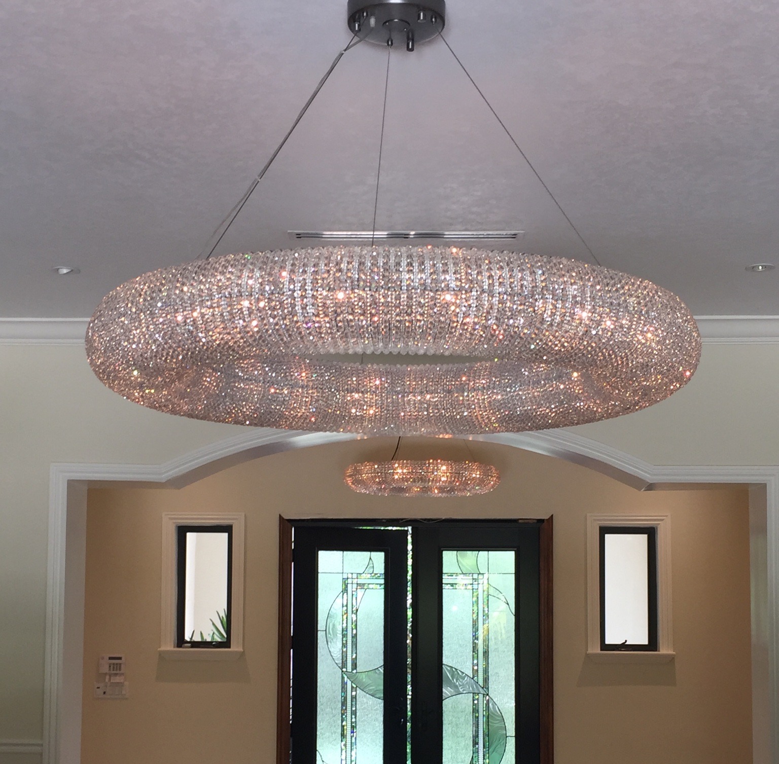 A large torus shaped light hung in the ceiling of a home's foyer.